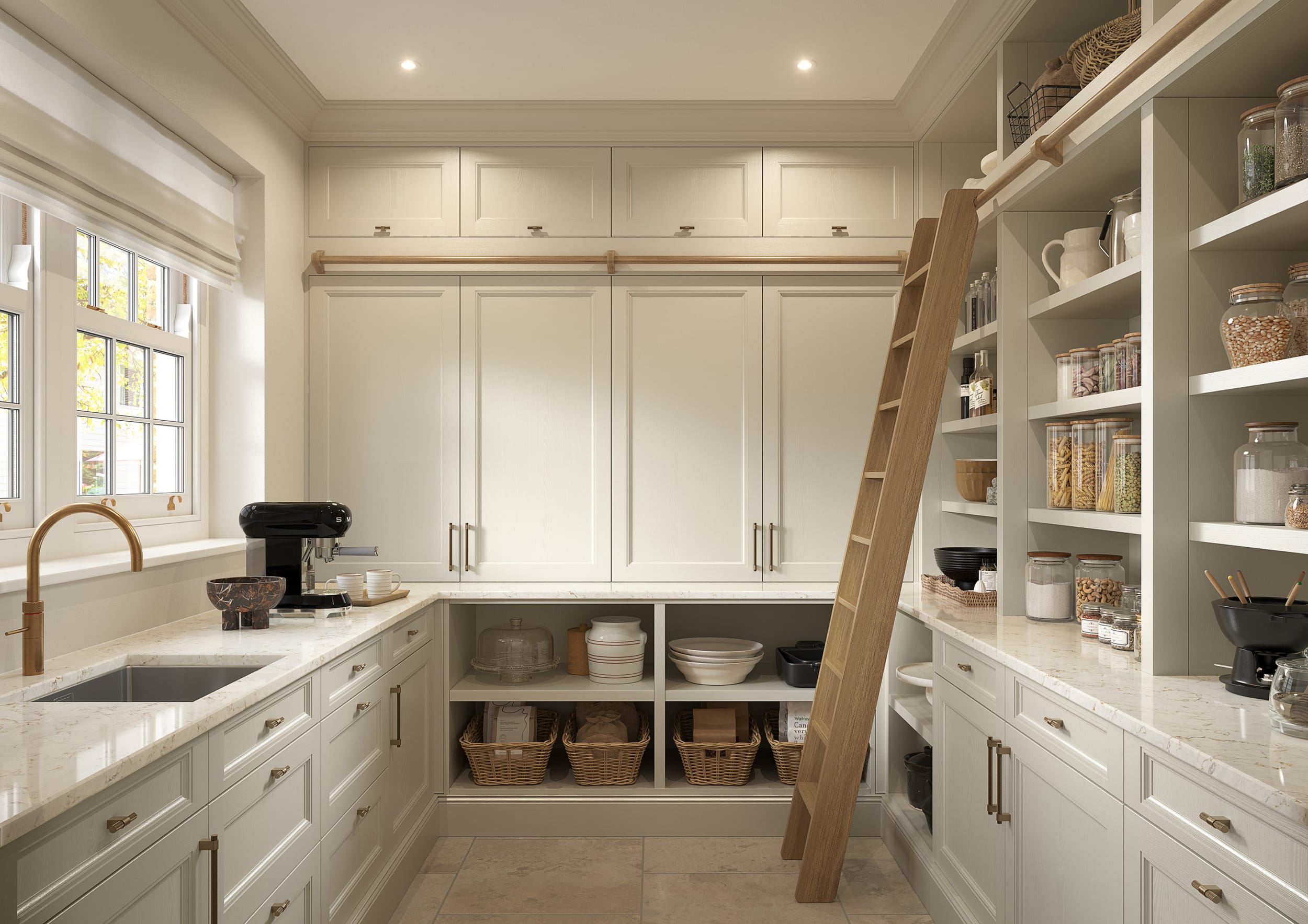 A beautifully designed kitchen pantry featuring elegant, shaker-style cabinetry in a soft cream hue. The room is bathed in natural light streaming through a large, multi-pane window dressed with a Roman blind. A marble-effect worktop runs along the cabinetry, paired with a brushed brass tap and an undermount sink. Open shelving displays neatly organised jars, baskets, and kitchenware, adding both functionality and charm. A sliding ladder leans against the tall cabinetry, providing access to upper storage, while the neutral colour palette is complemented by warm wooden and brass accents, creating a timeless and sophisticated aesthetic.